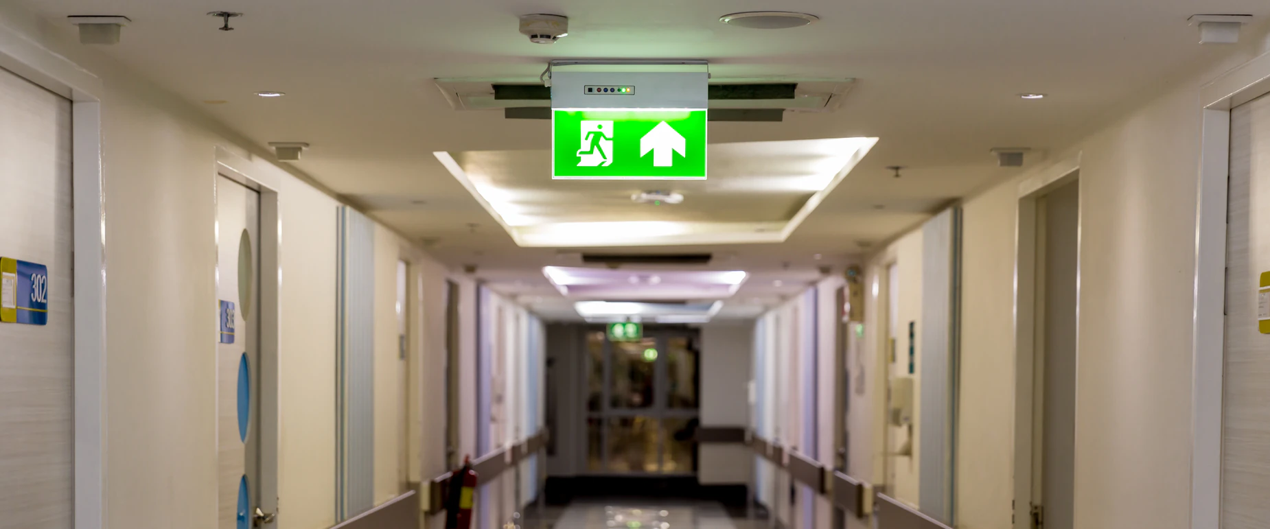 Illuminated emergency exit sign above a corridor escape route