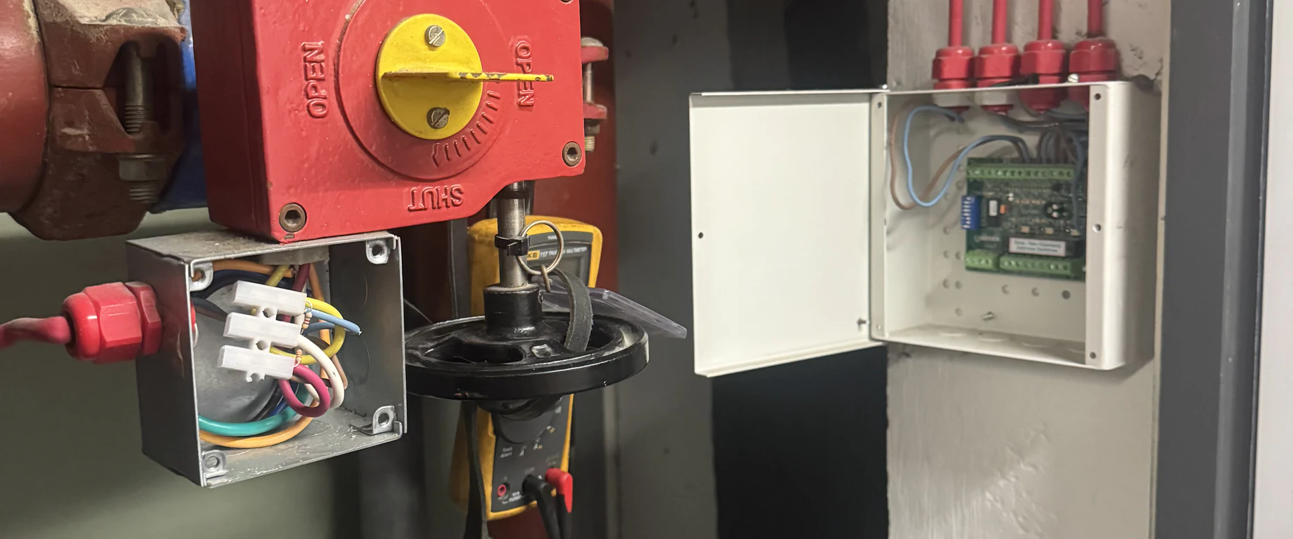 Engineer taking readings from a monitored sprinkler valve actuator with a multimeter during fault diagnosis