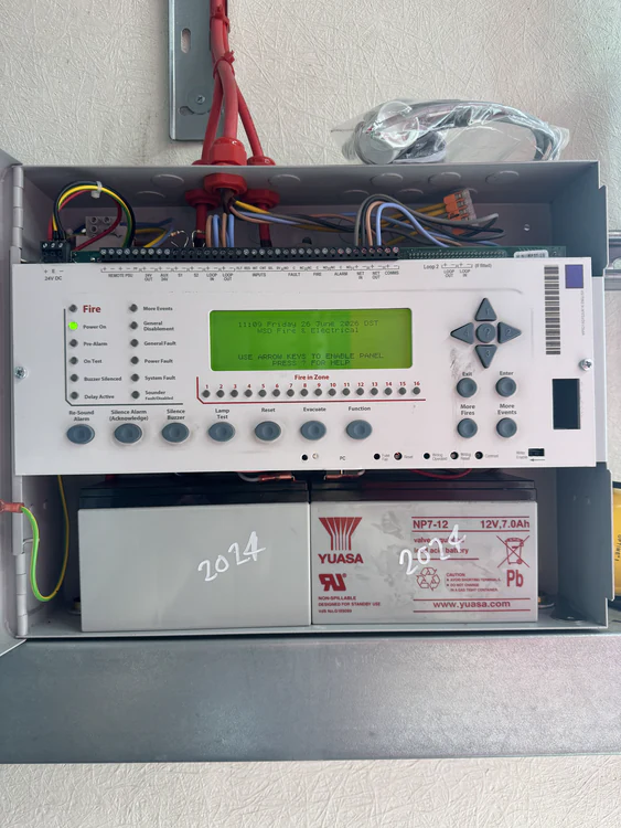 Fire alarm panel opened for service showing the loop terminations, control card and standby batteries
