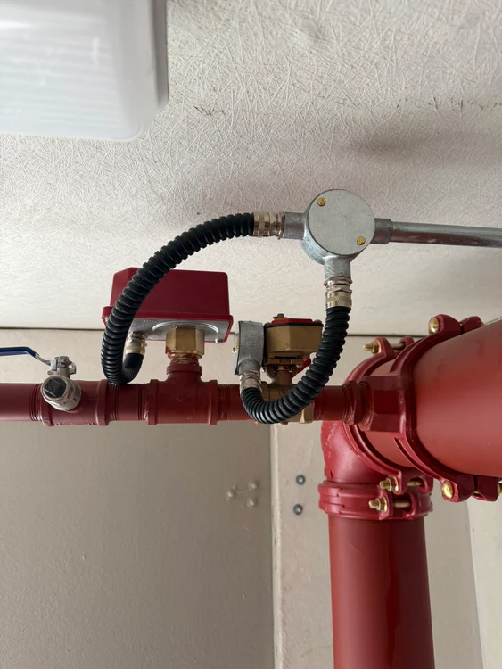 Flow switch and pressure switch wired into a sprinkler branch pipe at ceiling level